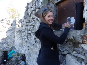 Katie Craney painting on a rusted boiler door on the Fort Seward barracks ruins. (Emily Files)