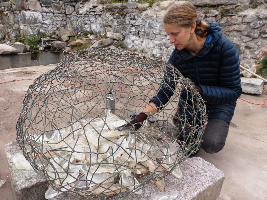 Sarah Bishop finishes up her installation by placing glass fish in a copper wire nest. (Emily Files)